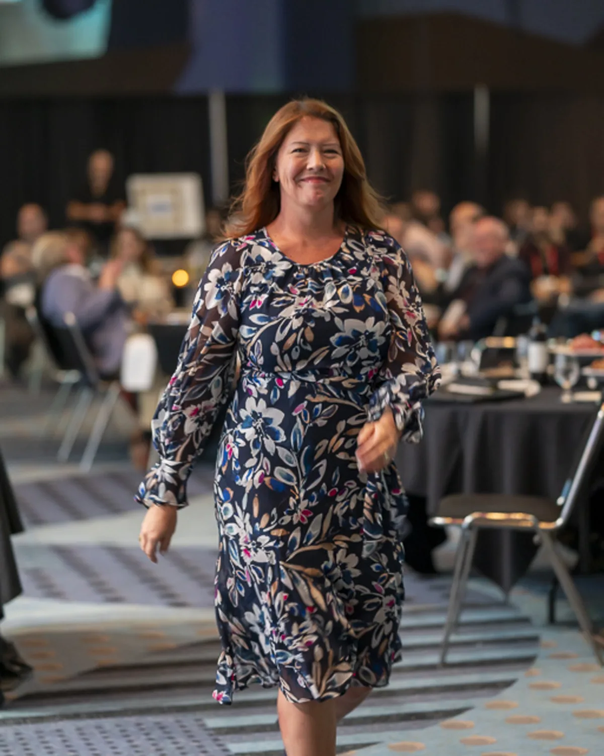 Confident woman walking through banquet hall at a professional convention
at the Denver Convention Center, captured with documentary-style event photography