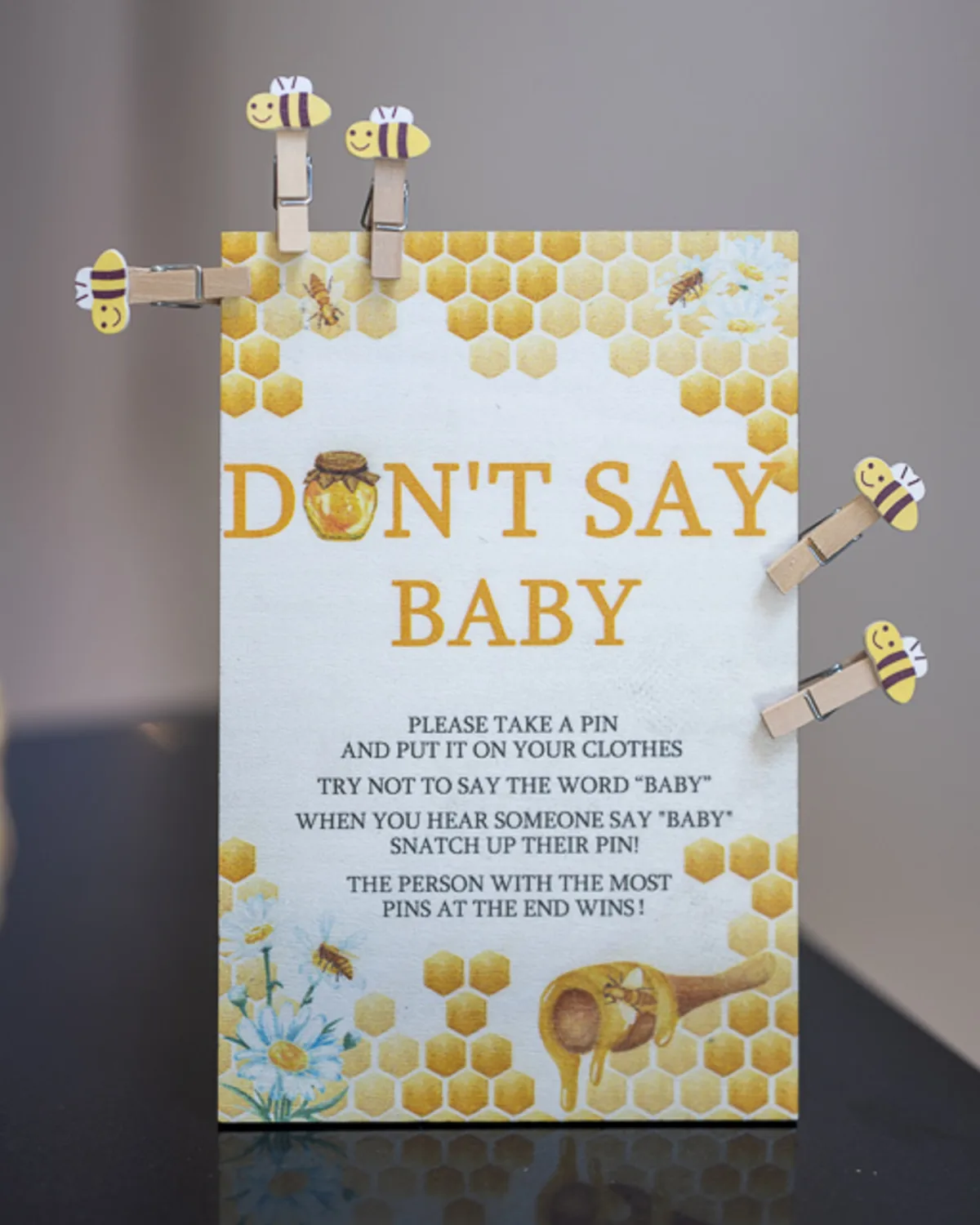 Baby shower game sign reading 'Don't Say Baby' with bee-themed pins,
photographed at a themed event in Denver