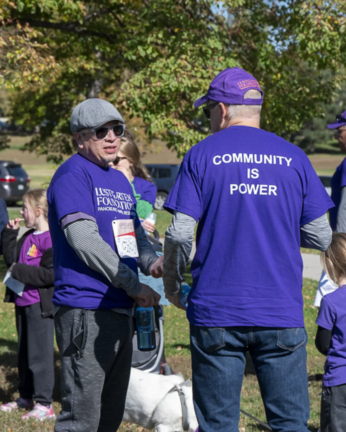 Participants at a Lustgarten Foundation benefit walk at Sloan Lake Park in
Denver, wearing matching shirts with 'Community is Power' slogan, captured at a
nonprofit event
