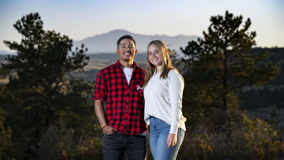 Smiling interracial couple posing outdoors in casual clothes during golden
hour portrait session near Denver with mountains in the background
